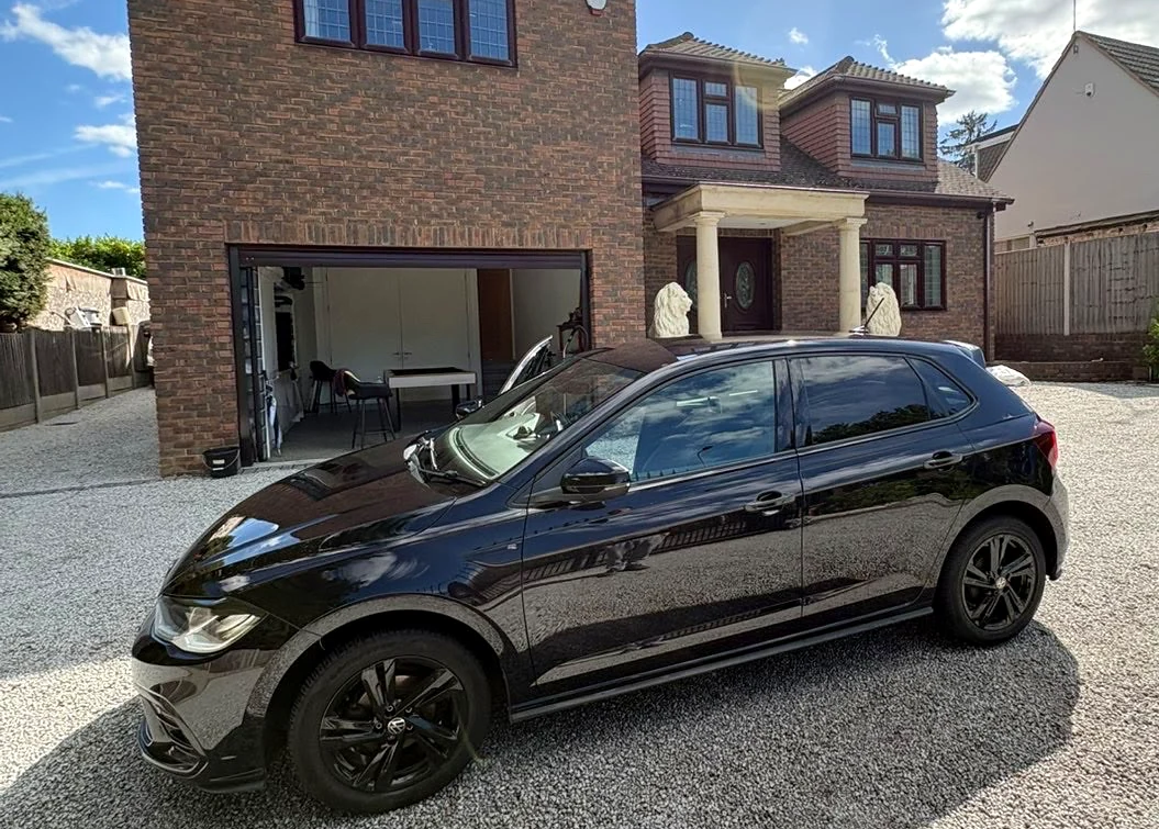 Side view of the black hatchback outside a brick house