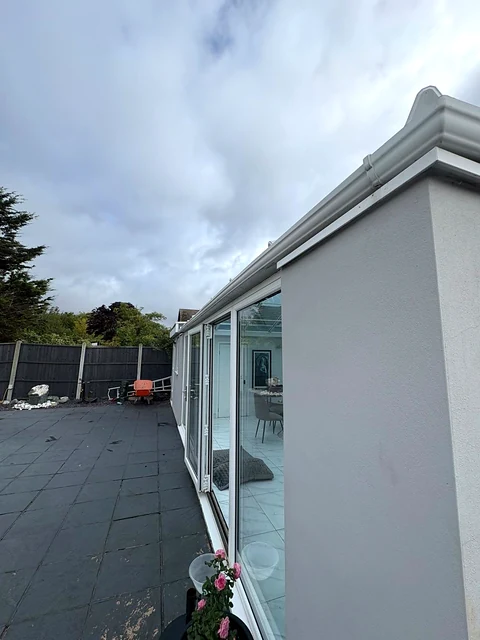 White conservatory frames and glazing beside a paved patio