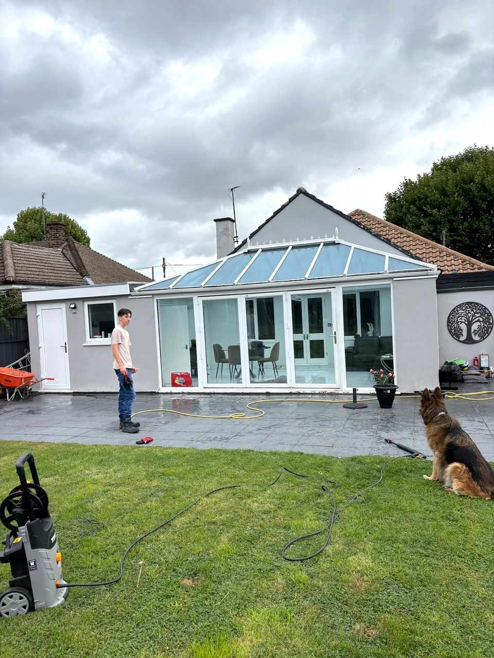 A real exterior cleaning visit, with a person, pressure washer and dog in the garden
